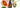 Glass bottle of orange essential oil surrounded by fresh blood orange slices on a white surface